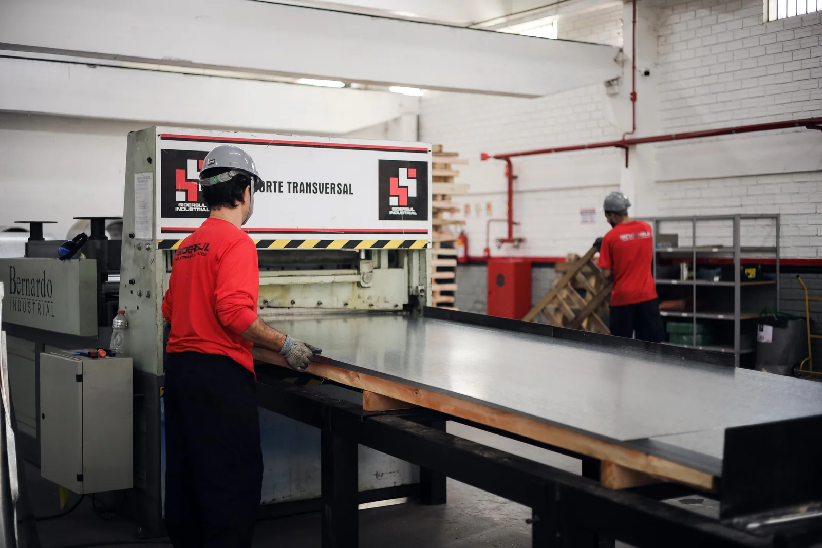 Equipe operando a linha de corte transversal da Sidersul Industrial